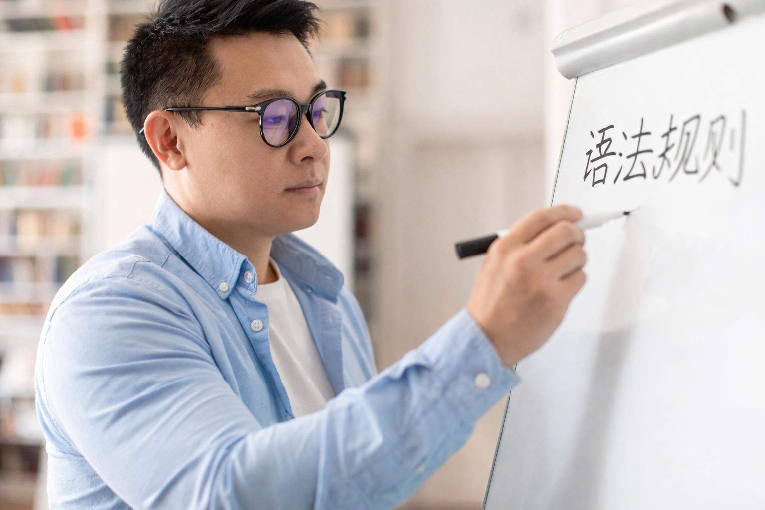 a male teacher writing 'grammar rules' on whiteboard